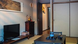 Un salon avec un téléviseur, un meuble en bois et une table sur laquelle se trouve un objet bleu.