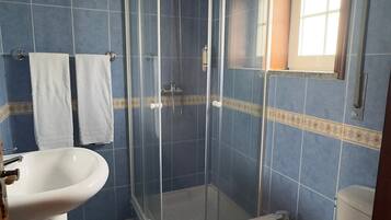 Un baño con ducha de vidrio, dos lavamanos, un bidé y un inodoro.