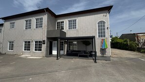 A two-story building with a covered outdoor seating area, a garage door, and a sign that reads 'FLAVORS.'