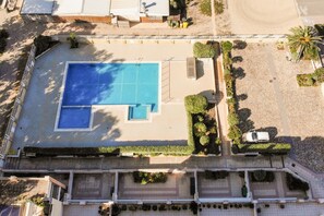 Vista aérea de una propiedad con piscina, terraza techada y jardín ajardinado.