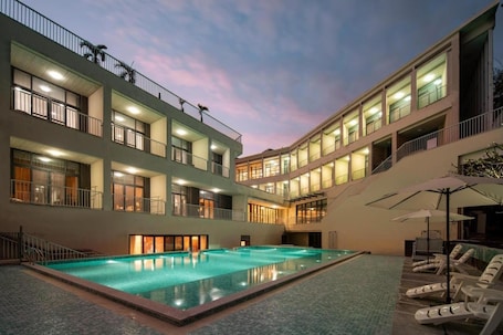 A multi-story hotel with a central swimming pool, balconies, and outdoor seating.