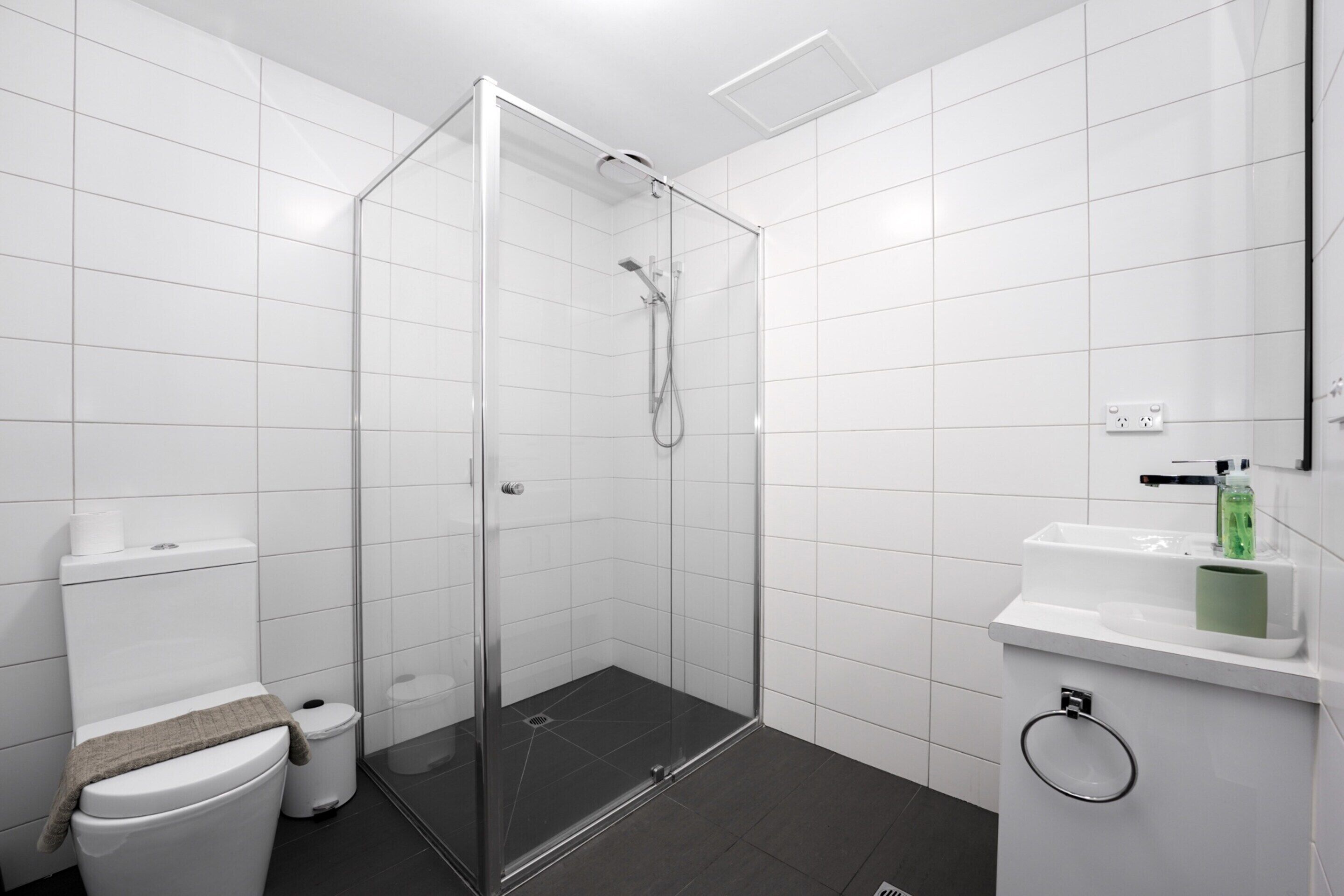 A bathroom with a glass-enclosed shower, a toilet, a sink, and a mirror.