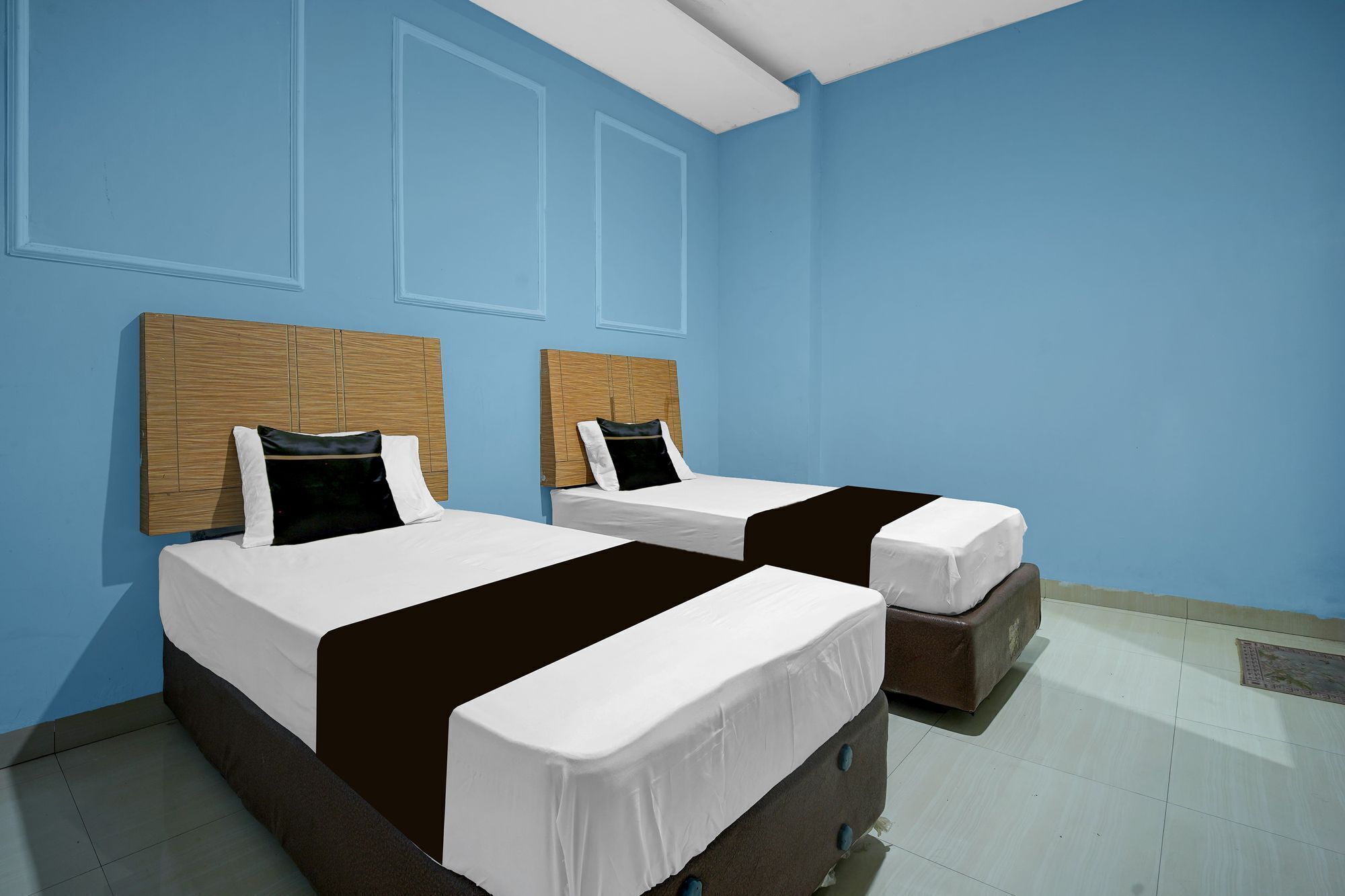 A hotel room with two beds, a wooden headboard, and a tiled floor.
