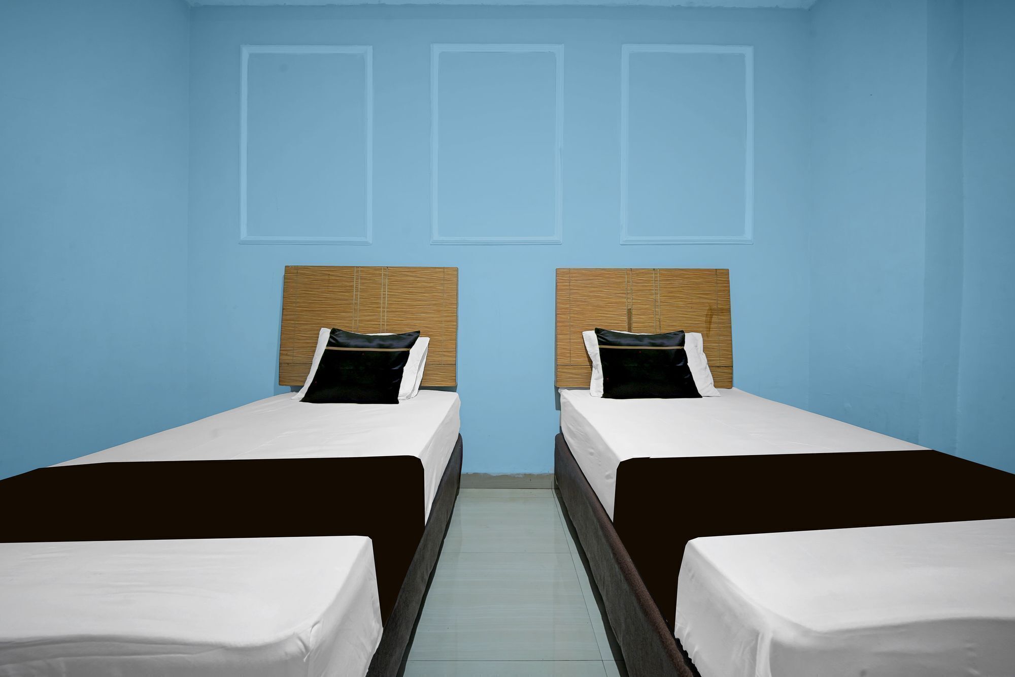 Una habitación con dos camas, cada una con cabecero de madera y ropa de cama blanca.