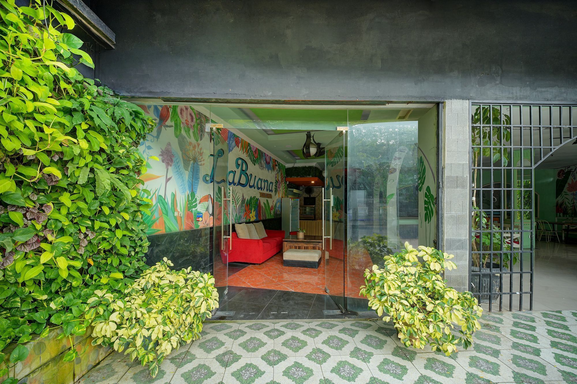 A room with a red sofa, a glass door entrance, and a mural on the wall.