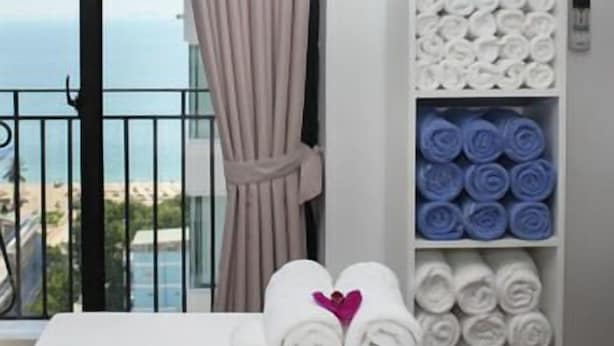 Een hotelkamer met balkon, een handdoekrek met opgerolde handdoeken en een plank met toiletartikelen.
