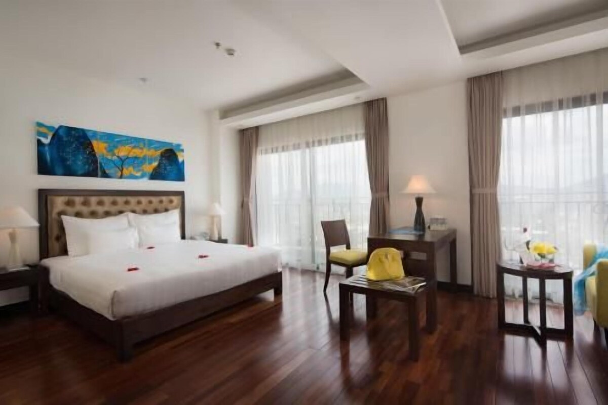 Habitació d'hotel amb un llit gran, un escriptori, una cadira i una finestra amb cortines.