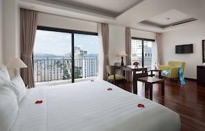 Une chambre d’hôtel avec un grand lit, un bureau, une chaise et un téléviseur.