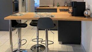 A modern kitchen with a central island, bar stools, built-in appliances, and a large window.