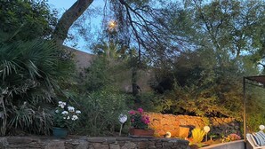A stone wall with a fire feature, outdoor seating, and various plants.