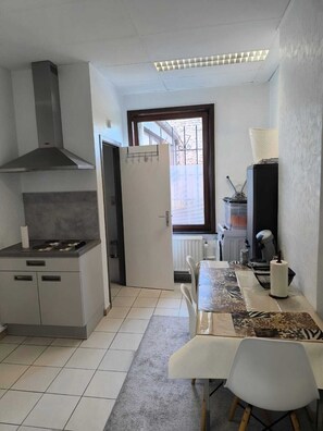 Una cocina compacta con estufa, campana extractora y comedor con mesa y sillas.