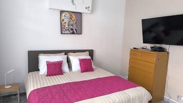 A bedroom with a bed, a television, a dresser, and wall art.