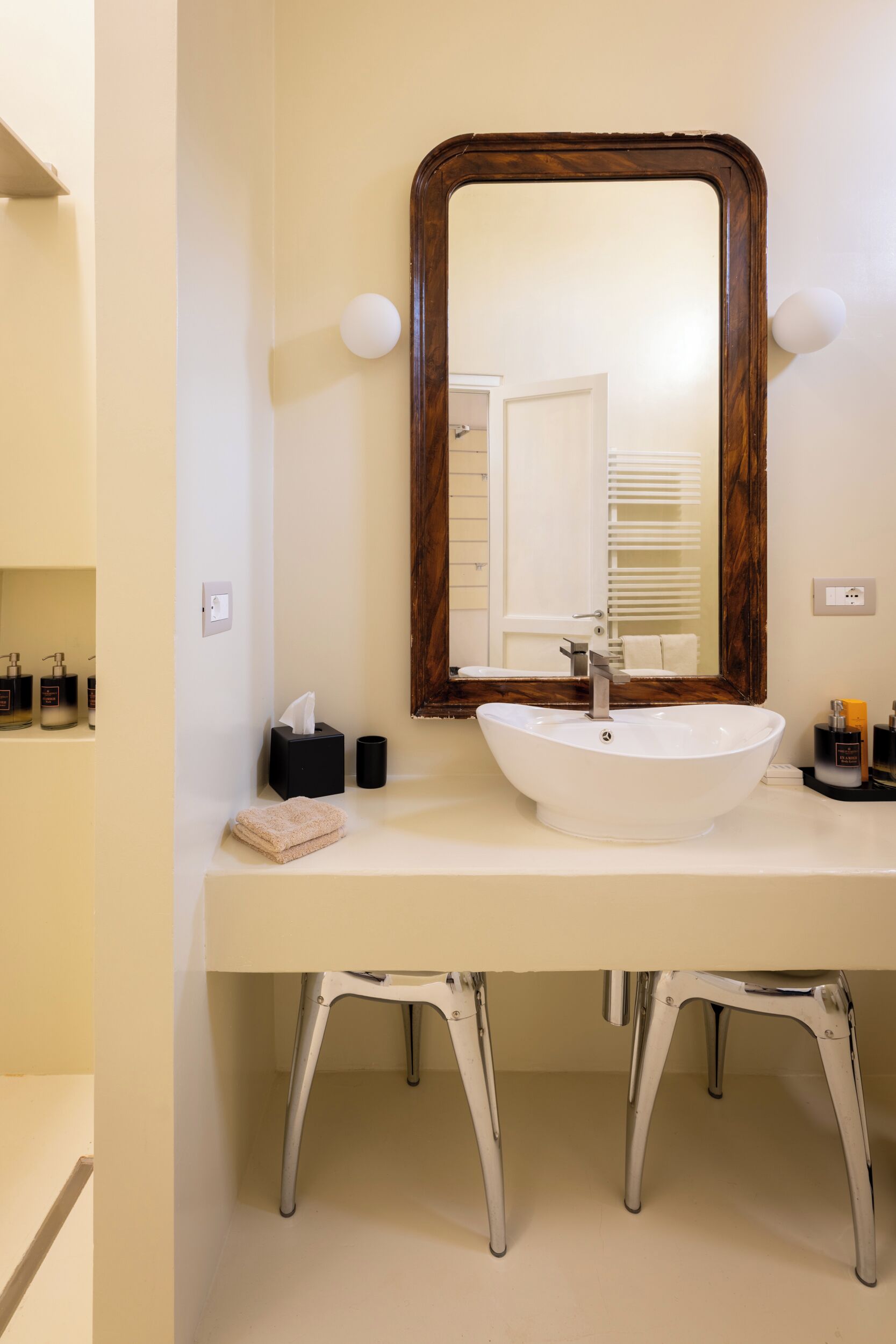 Une salle de bain avec un lavabo blanc, un miroir encadré en bois et un meuble-lavabo blanc.