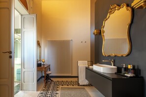 A bathroom with a white sink, a large mirror, and a radiator. - Villani Lubelli Apartments (Cannole)