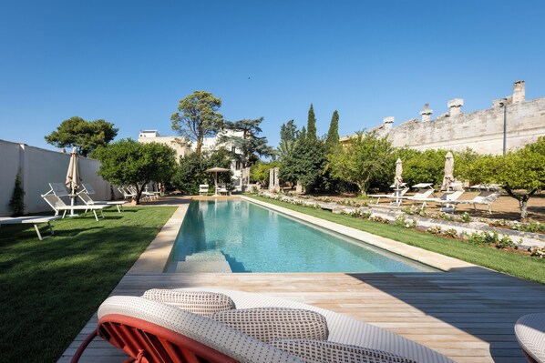 A swimming pool with lounge chairs and a wooden deck. - Villani Lubelli Apartments (Cannole)