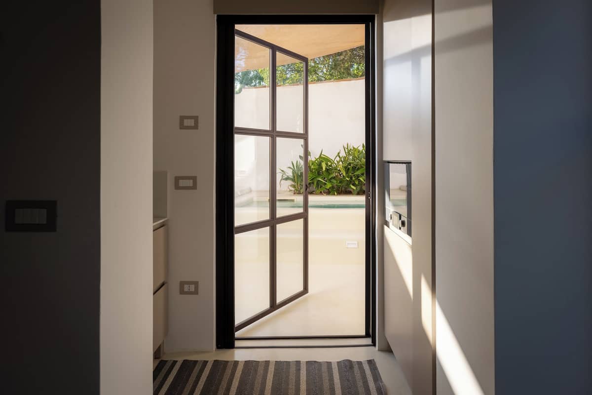 Un pasillo moderno con una puerta de cristal que da a un patio.