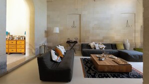 Un salon moderne avec un canapé foncé, une table basse en bois et un tapis à motifs. On y trouve une cheminée avec une manteau de cheminée et une petite table d’appoint.