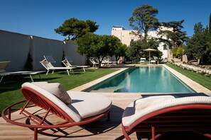 A poolside area with lounge chairs, a pool, and a building in the background. - Villani Lubelli Apartments (Cannole)