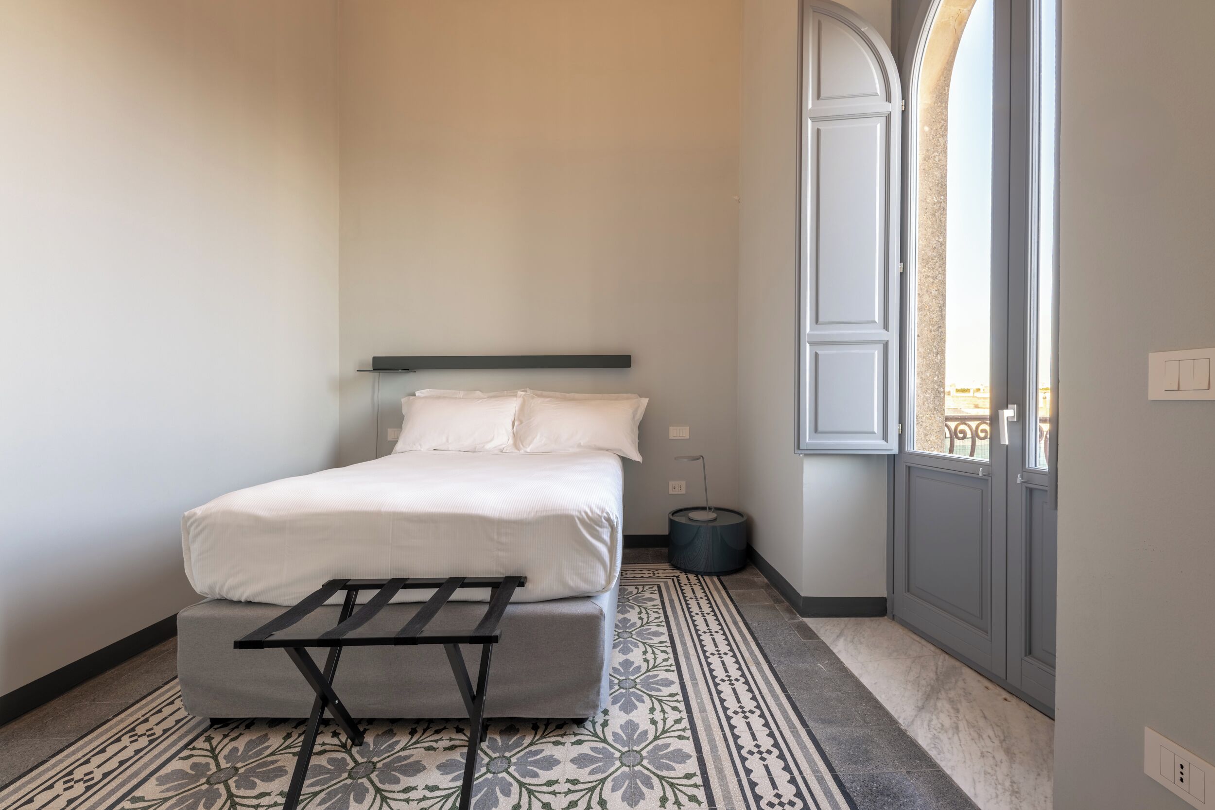 Une chambre à coucher avec un lit, une petite table, un tapis à motifs et une fenêtre donnant sur un beau paysage.