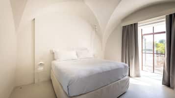 Een moderne slaapkamer met een groot bed, een nachtkastje en een raam met gordijnen.