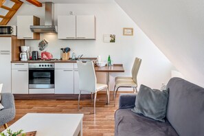 Et moderne køkken med hvide skabe, en komfur og et spiseområde med bord og stole.