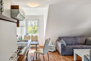 A compact living space with a kitchenette, dining area, and a couch. - Sunset Vacation Apartment – Your Retreat in the Heart of Nature (Herzberg am Harz)