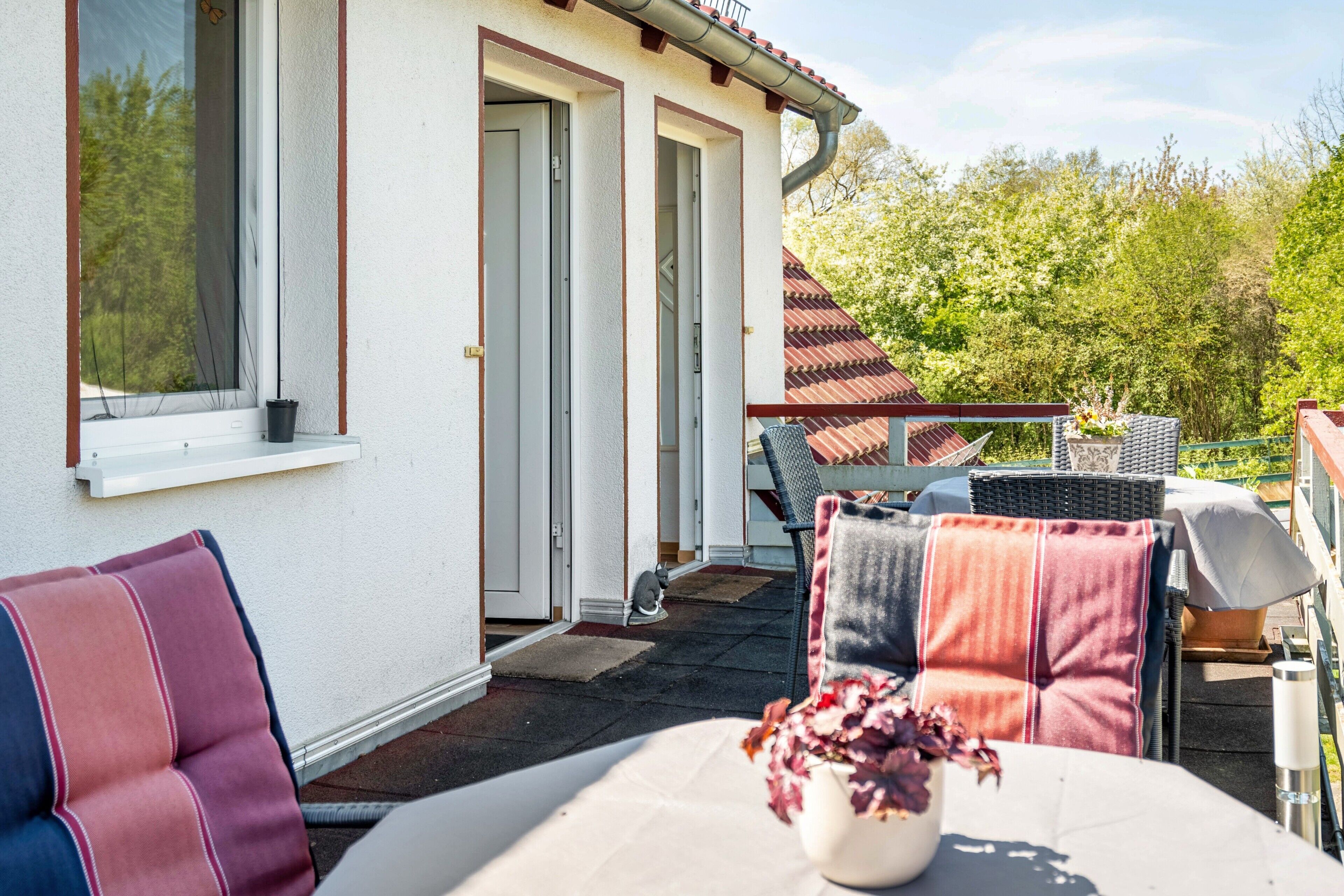 Une terrasse avec une table, des chaises et un pot de fleurs.
