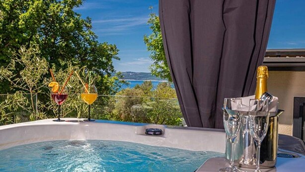 Ein Whirlpool mit Getränken und einer Champagnerflasche, mit Blick auf eine schöne Aussicht.