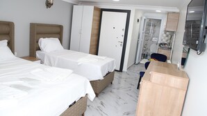 A hotel room with two beds, a wardrobe, a desk, and a television. - Laos Otel & Apartment (Istanbul)