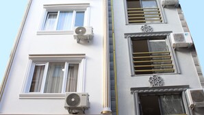 A multi-story building with air conditioning units, a central vertical yellow line, and a door with a sign. - Laos Otel & Apartment (Istanbul)