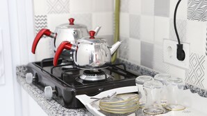 A kitchen with a gas stove, a kettle, and a tray with glassware. - Laos Otel & Apartment (Istanbul)