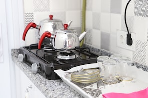 A kitchen with a gas stove, a kettle, and a tray with glassware.