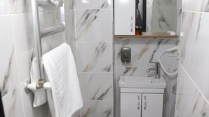 A bathroom with a toilet, sink, mirror, towel rack, and marble tiles. - Laos Otel & Apartment (Istanbul)