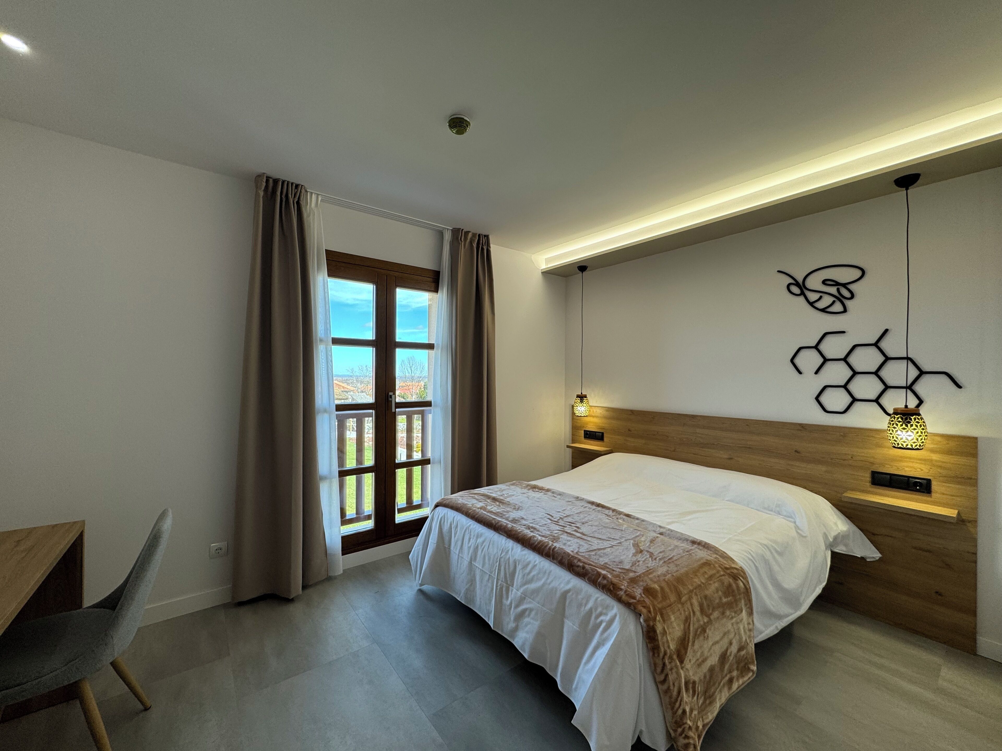 Un dormitorio moderno con una cama, un escritorio y vistas a través de una puerta.