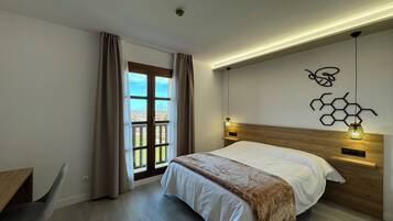 Un dormitorio moderno con una cama, un escritorio y vistas a través de una puerta.