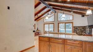 Eine Küche mit Holzausstattung, Granitarbeitsplatten und einer Wand mit Naturstein.