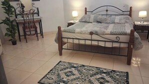 A bedroom with a bed, bedside lamps, a chair, a small table, and a potted plant. -  Entire rental, Perfect Abbass el akkad flat with balcony (cairo)