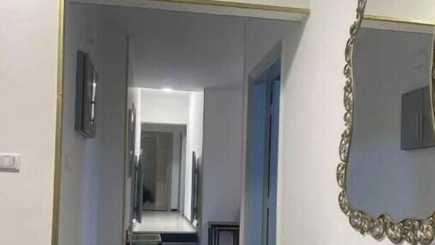 Un couloir avec un meuble-lavabo en marbre et un grand miroir décoratif.