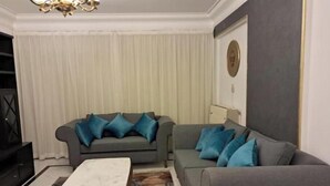 Un salon avec deux canapés gris, une table basse en marbre et un lustre.