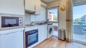 A modern kitchen with built-in appliances, a window with a view, and a balcony. - Cosy Renovated Apartment Near the Beach With Balcony (Lattes)