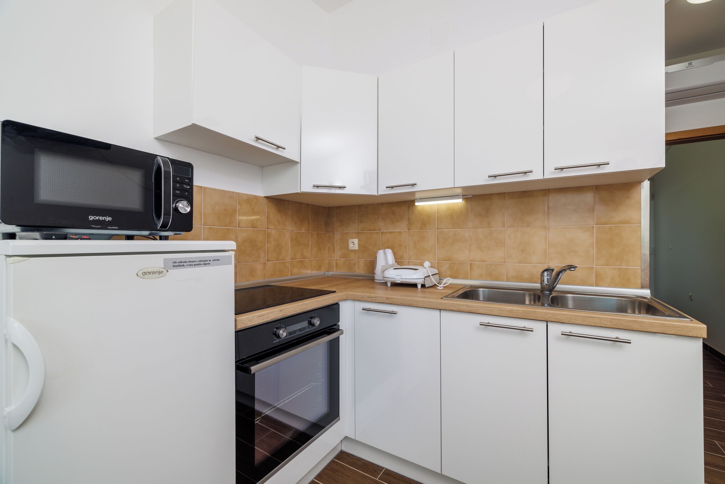 Una cucina moderna con mobili bianchi, forno a microonde integrato, tostapane ed elettrodomestici.
