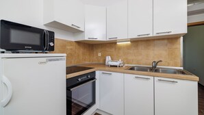 Une cuisine moderne avec des meubles blancs, un four à micro-ondes encastré, un grille-pain et un lave-vaisselle.