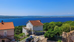 Une maison située sur la côte, avec un toit recouvert de tuiles rouges, un balcon et une vue sur la mer.