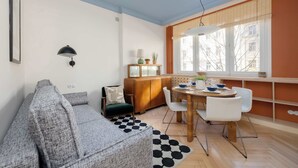 A modern living room with a sofa, dining table, chairs, and a cabinet. - Sunny Apartment in the Center | Place to Work (Warszawa)