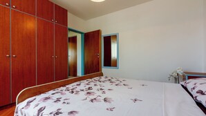 Ein Schlafzimmer mit einem Holzschrank, einem Bett mit floralem Bettzeug und einem Spiegel an der Wand.