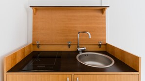 Une cuisine équipée d’une plaque de cuisson à induction intégrée, d’un évier en acier inoxydable et de meubles de rangement en bois.