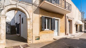 Un bâtiment doté d’une façade en pierre, d’un balcon avec une rambarde en métal et d’une porte à volets.