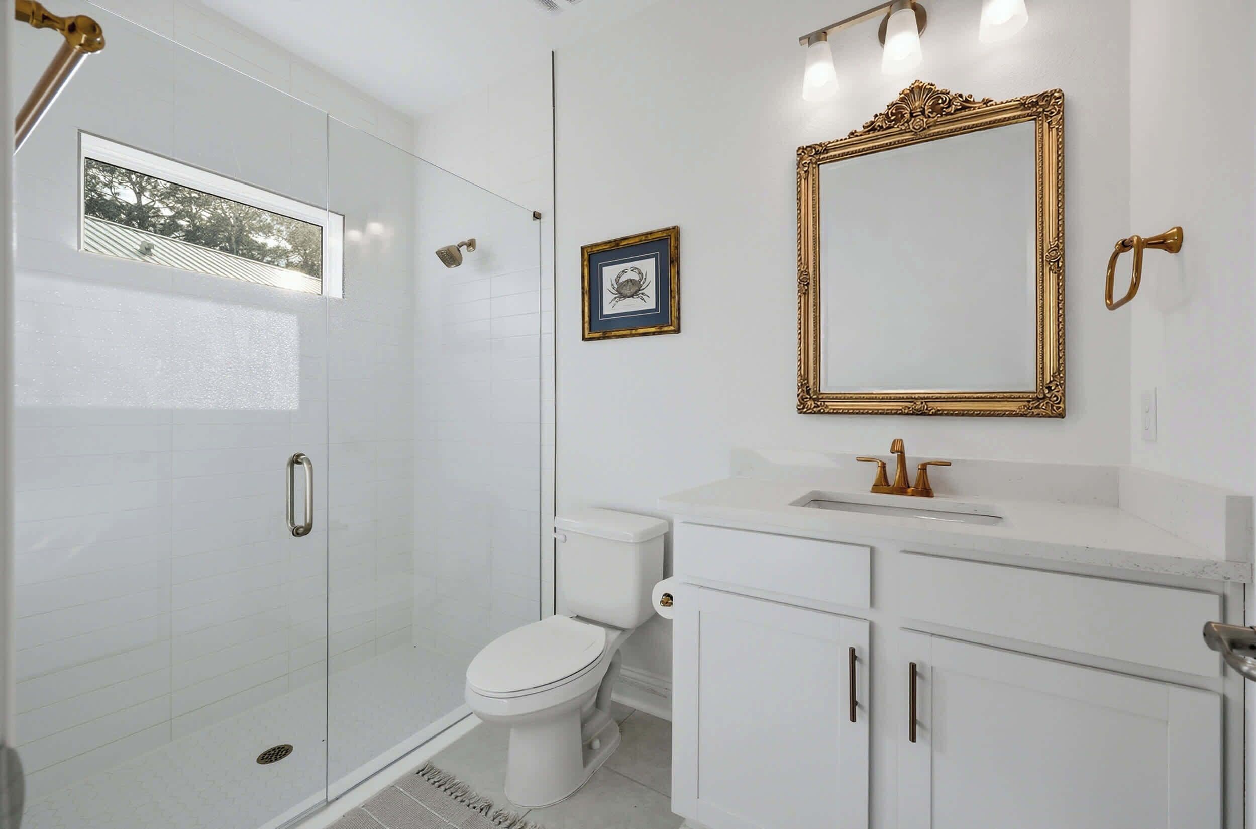 Un baño con inodoro, ducha, lavamanos y espejo.