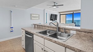 Una cocina moderna con encimeras de granito, lavamanos de acero inoxidable y un ventilador de techo.