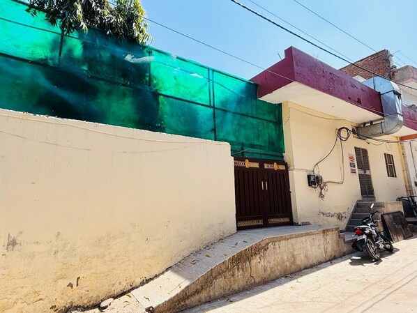 A building with a green wall, a brown door, and a motorcycle parked outside.